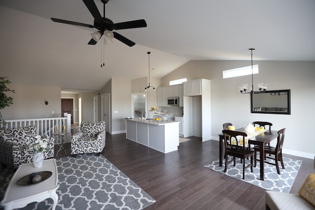 living room with dark hardwood / wood-style floors, sink, ceiling fan with notable chandelier, and vaulted ceiling