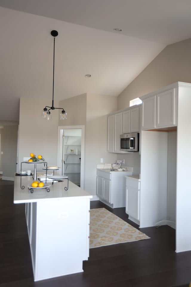 kitchen featuring lofted ceiling, a kitchen island with sink, sink, dark hardwood / wood-style flooring, and white cabinetry