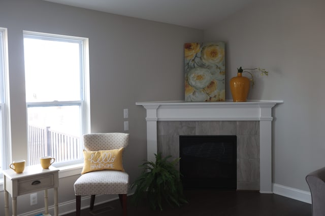 sitting room with a tile fireplace and dark hardwood / wood-style flooring