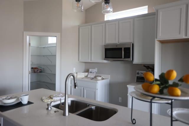 kitchen featuring white cabinets, sink, and hanging light fixtures