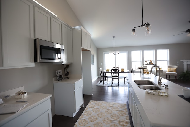 kitchen featuring vaulted ceiling, a kitchen island with sink, sink, decorative light fixtures, and hardwood / wood-style flooring