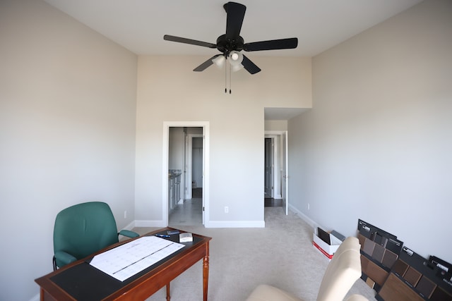 carpeted home office with ceiling fan and a towering ceiling