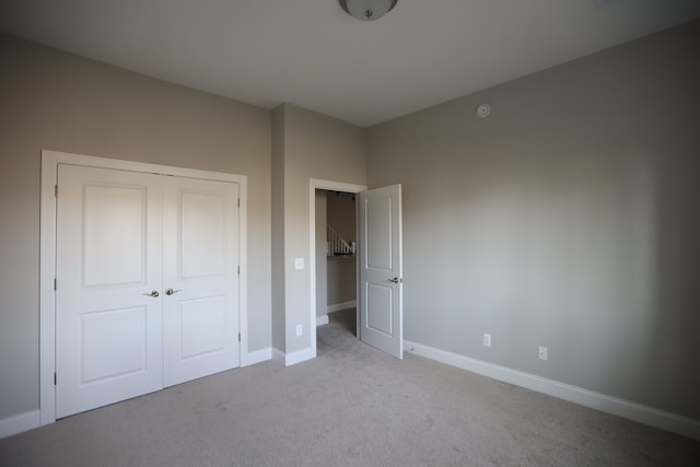 unfurnished bedroom featuring light carpet and a closet