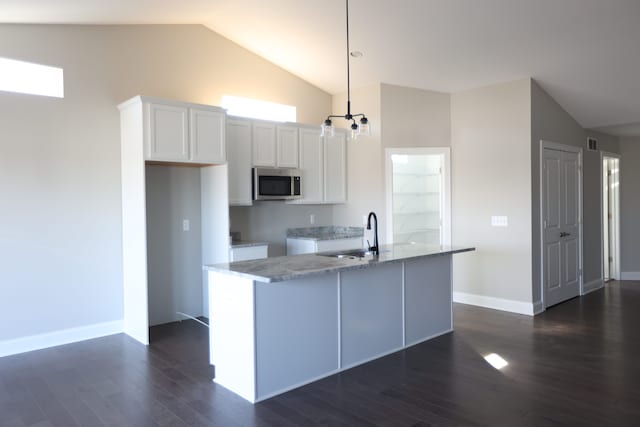 1012 Camellia Cir Unit 48, Howell, MI 48843 - kitchen featuring stainless steel microwave, a sink, white cabinetry, dark wood-style flooring, and a center island with sink