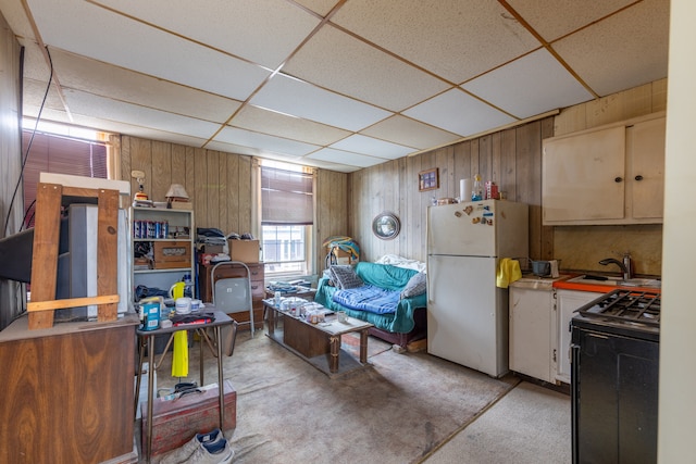 kitchen featuring electric range, a drop ceiling, sink, wood walls, and white fridge