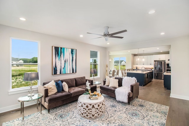 living room featuring ceiling fan, sink, and light wood-type flooring