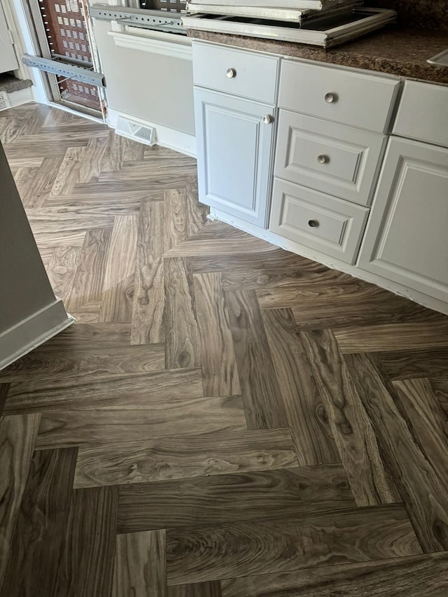 details with white cabinetry and parquet flooring