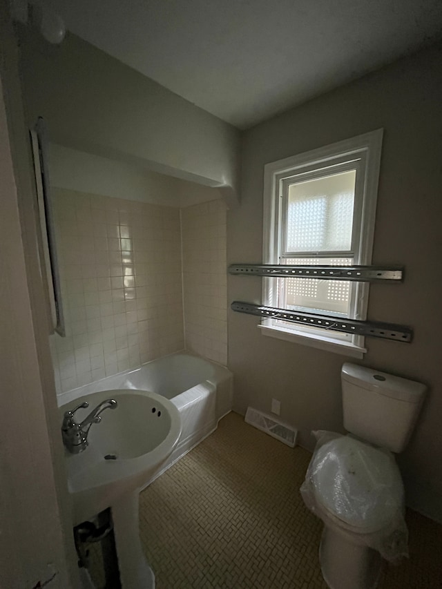 bathroom featuring tile patterned floors, a tub, and toilet