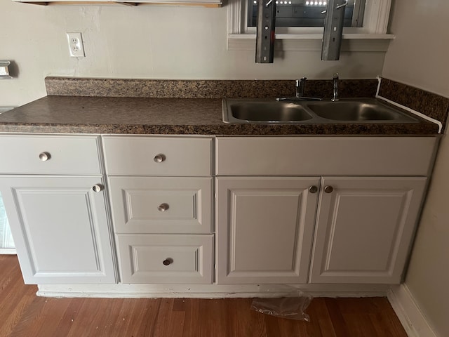 18109 Cornwall St, Detroit, MI 48224 - kitchen with dark countertops, a sink, wood finished floors, and white cabinets