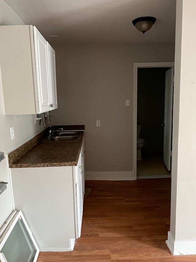 18109 Cornwall St, Detroit, MI 48224 - kitchen with light wood-style flooring, a sink, white cabinets, baseboards, and dark countertops