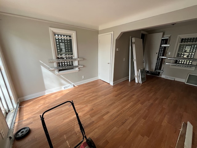 unfurnished living room with hardwood / wood-style floors and crown molding