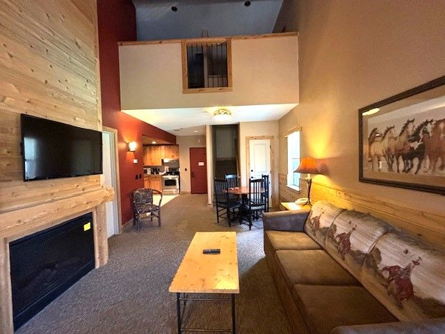 living room featuring carpet flooring, wood walls, and a towering ceiling