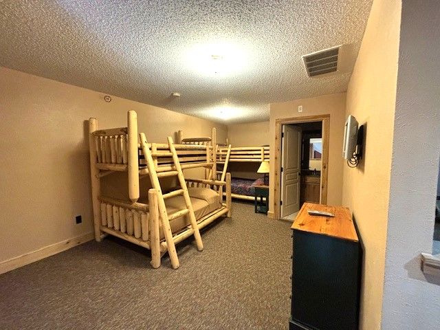 bedroom featuring dark colored carpet and a textured ceiling