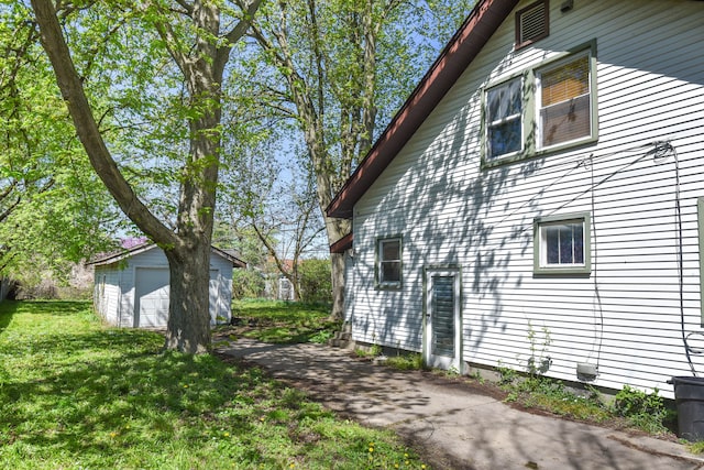 view of side of home featuring a garage, an outdoor structure, and a lawn