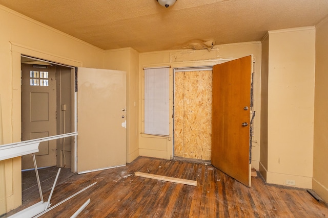 entryway with dark wood-type flooring, a textured ceiling, and ornamental molding