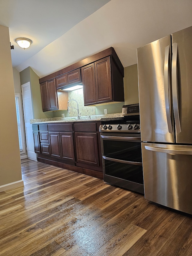 kitchen featuring sink, light stone countertops, appliances with stainless steel finishes, dark hardwood / wood-style flooring, and dark brown cabinetry