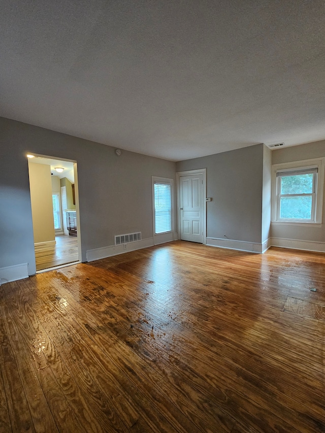 empty room with a textured ceiling and hardwood / wood-style flooring