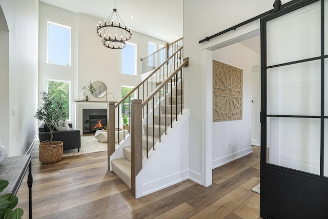 foyer featuring hardwood / wood-style floors, a barn door, a towering ceiling, and a chandelier