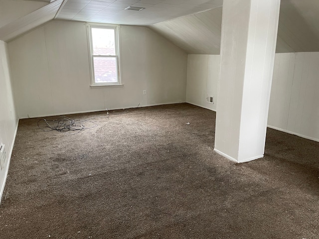 additional living space with dark colored carpet and vaulted ceiling