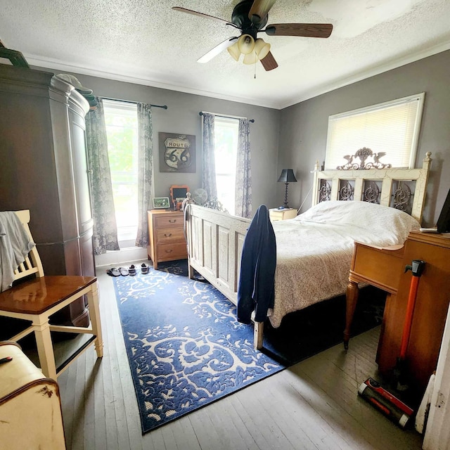 bedroom featuring a textured ceiling, dark hardwood / wood-style flooring, ceiling fan, and ornamental molding