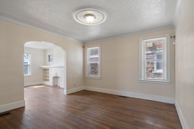 unfurnished room with ornamental molding, a textured ceiling, and dark wood-type flooring