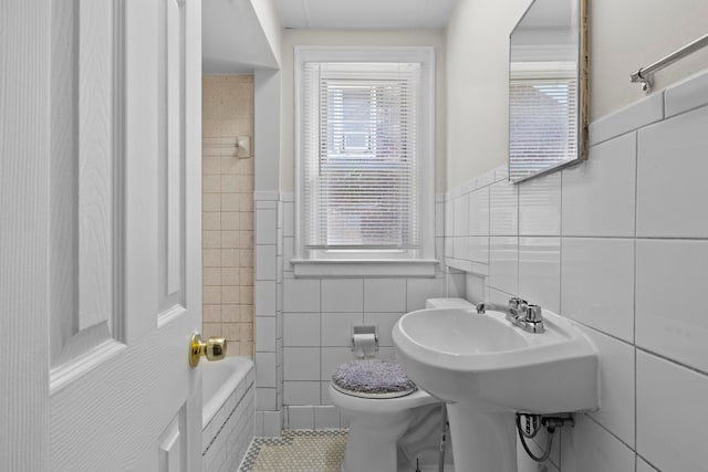 bathroom featuring a tub, tile walls, and toilet