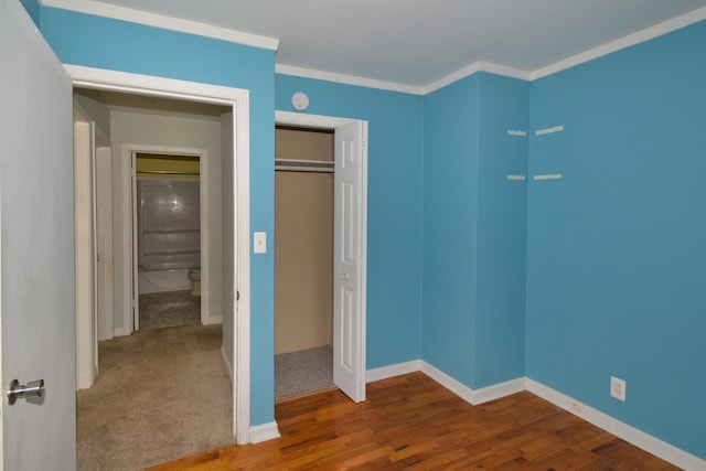 unfurnished bedroom with hardwood / wood-style floors, a closet, and crown molding