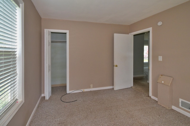 unfurnished bedroom featuring light carpet and a closet