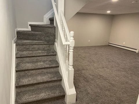 stairs featuring carpet flooring and baseboard heating