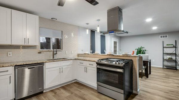 kitchen with appliances with stainless steel finishes, light stone counters, extractor fan, light hardwood / wood-style floors, and white cabinetry