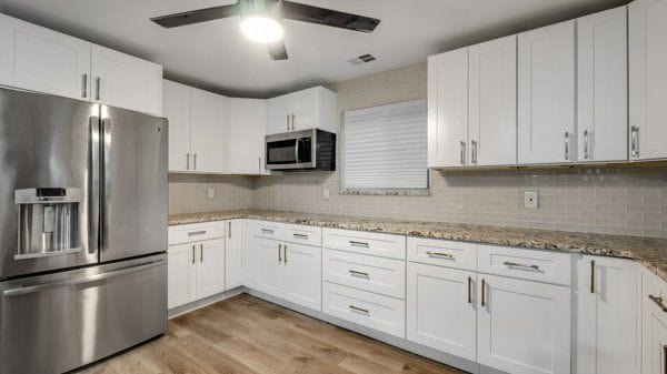 kitchen featuring white cabinets, appliances with stainless steel finishes, tasteful backsplash, and light hardwood / wood-style flooring