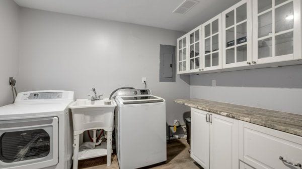 washroom with cabinets, electric panel, and washing machine and clothes dryer