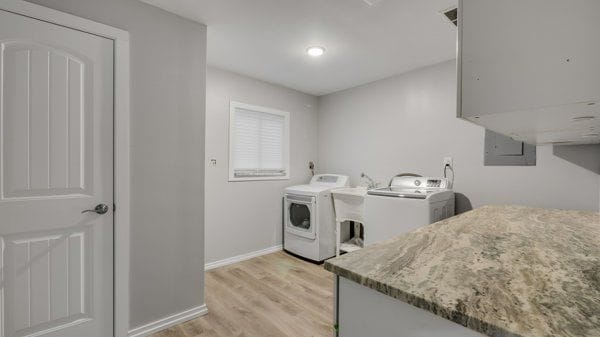 laundry room with independent washer and dryer, light hardwood / wood-style floors, and sink