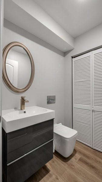 bathroom with toilet, vanity, and hardwood / wood-style flooring