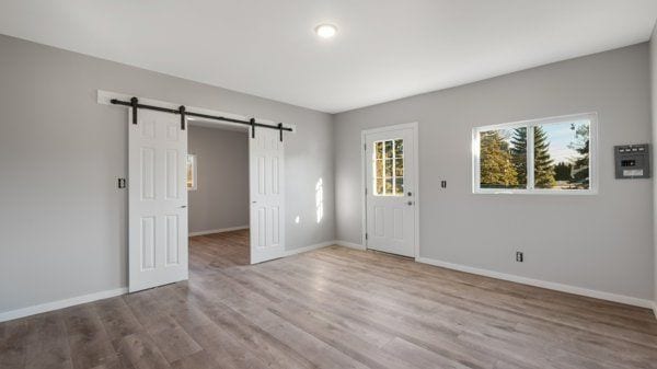 unfurnished room featuring a barn door and light hardwood / wood-style flooring