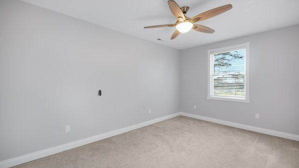 empty room featuring ceiling fan and light colored carpet