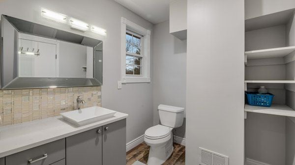 bathroom with decorative backsplash, vanity, wood-type flooring, and toilet