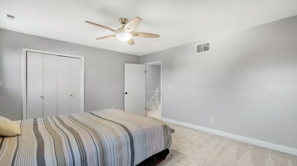 bedroom with a closet, ceiling fan, and light colored carpet