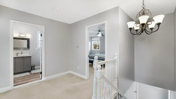 corridor with light colored carpet, a notable chandelier, and sink