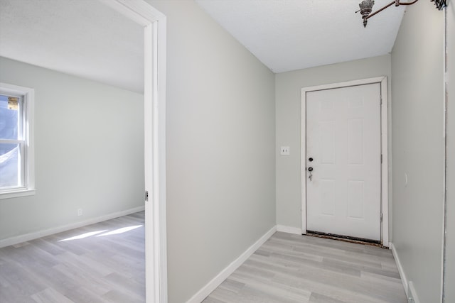 doorway featuring light wood-type flooring and a textured ceiling