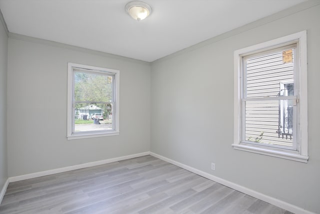 spare room featuring light wood-type flooring and crown molding