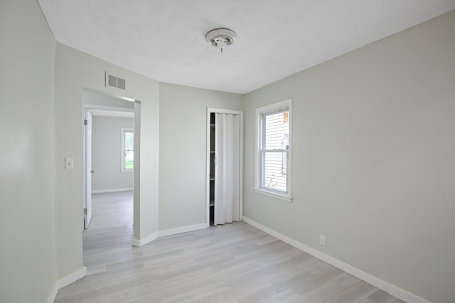 interior space featuring multiple windows, light hardwood / wood-style flooring, and a textured ceiling