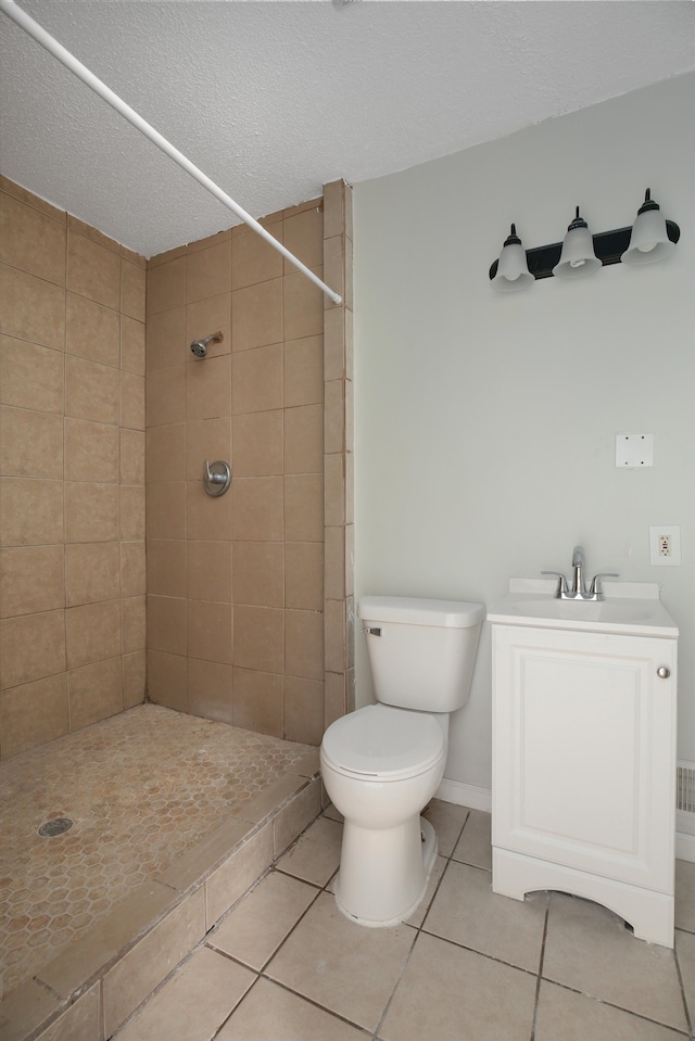 bathroom with tile patterned floors, a textured ceiling, vanity, tiled shower, and toilet