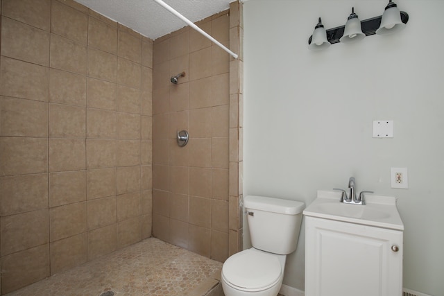 bathroom featuring vanity, toilet, a textured ceiling, and a tile shower