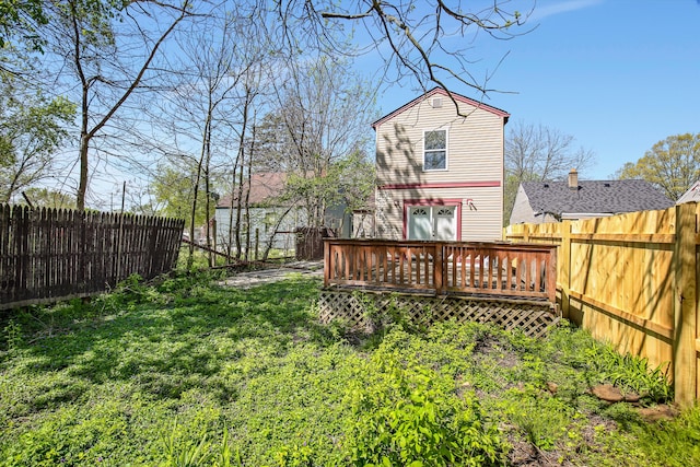 back of house with a deck and a lawn