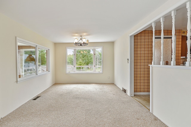 spare room with carpet flooring and an inviting chandelier