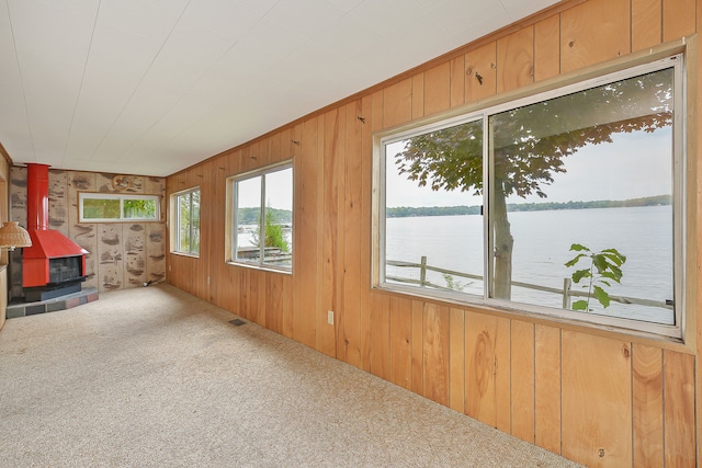 unfurnished sunroom featuring a wood stove and a water view