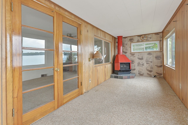 interior space with a wood stove, wood walls, and a water view