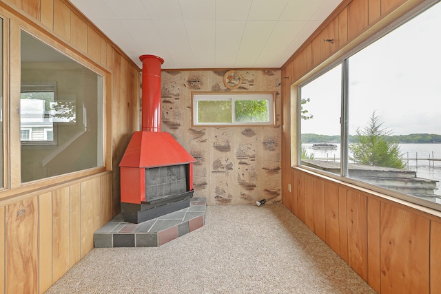 sunroom / solarium featuring a water view and a wood stove