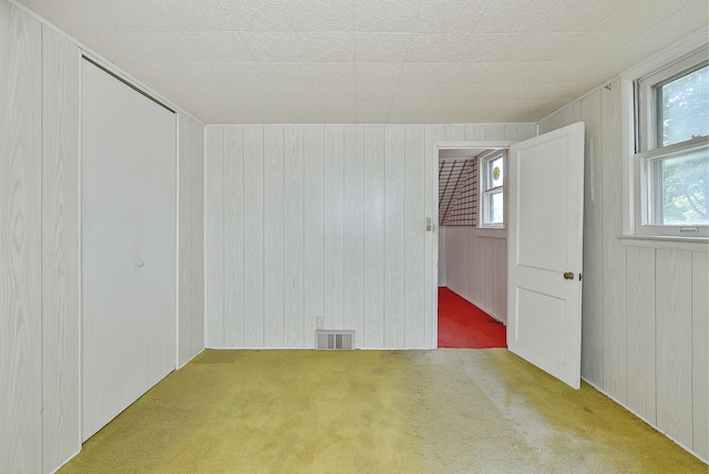 spare room with light carpet and wooden walls